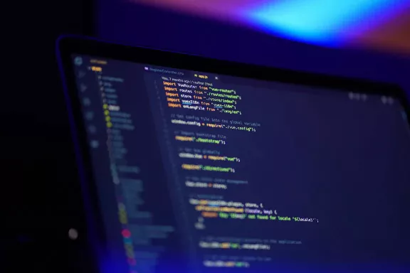 Image of a computer screen displaying code in a dark room.