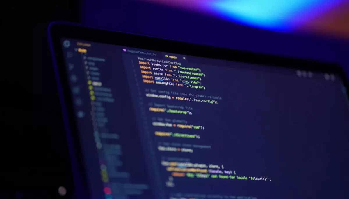 Image of a computer screen displaying code in a dark room.